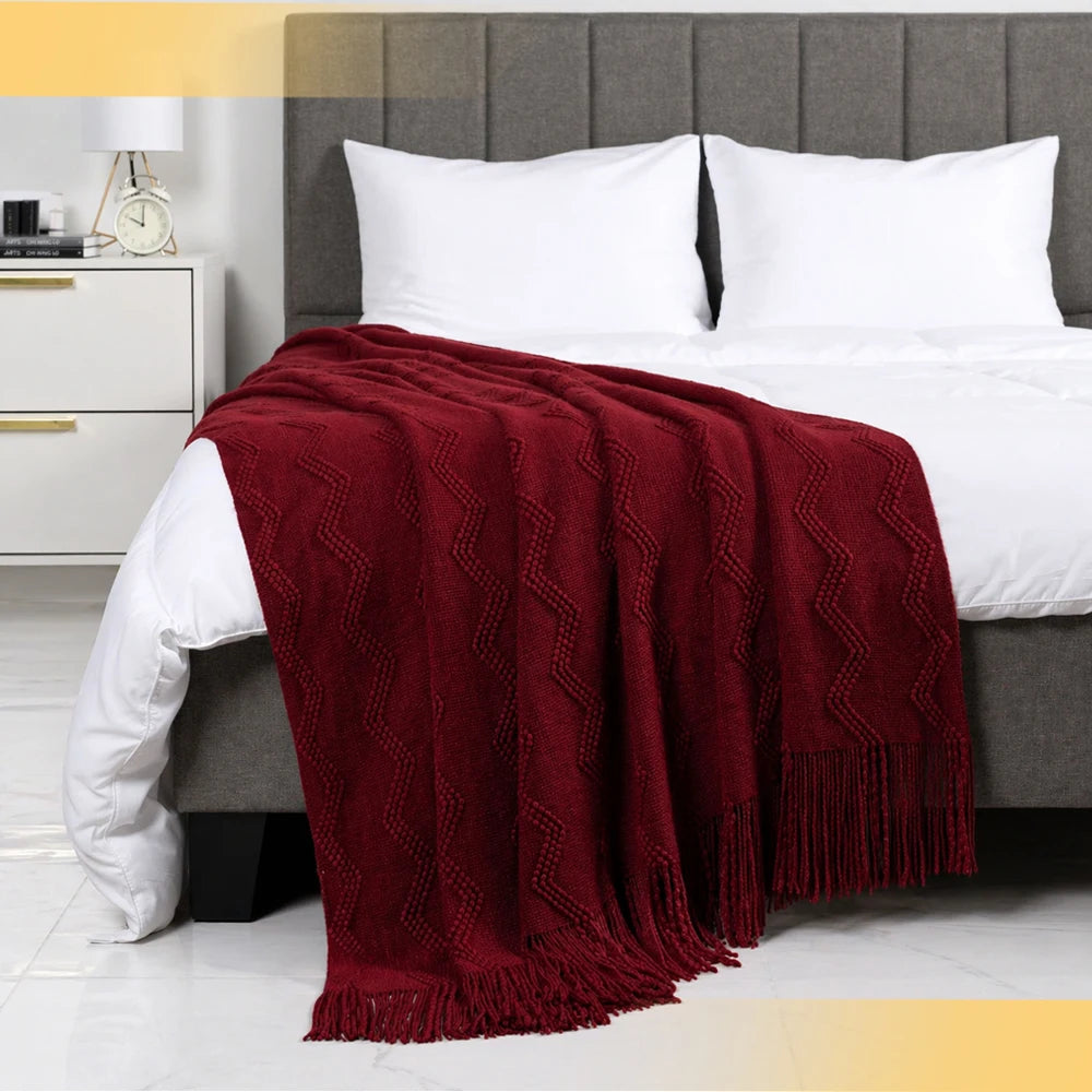 Soft textured burgundy throw blanket with chevron pattern and fringe, perfect for cozy couches and beds.
