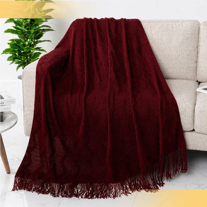 Close-up of a maroon red chevron knit throw blanket showcasing its texture and fringe details.
