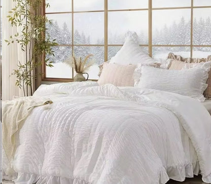 A styled bedroom featuring the White Ruffle Comforter Set paired with light wood accents, creating a serene environment.