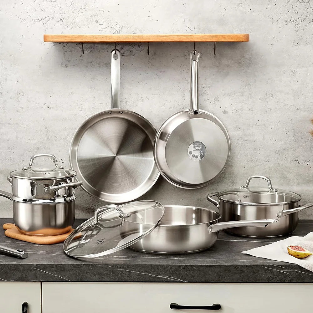 Set of stainless steel cookware on a kitchen counter with a concrete wall background.
