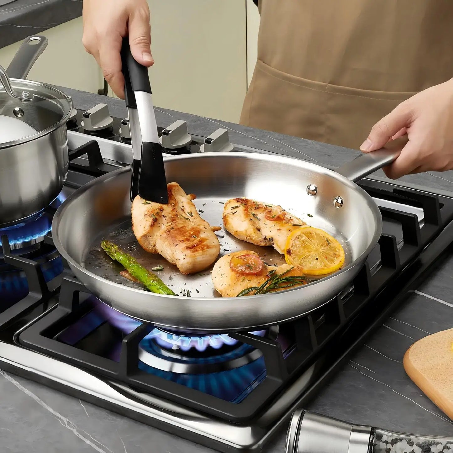 Person cooking chicken and vegetables in a frying pan on a gas stove.