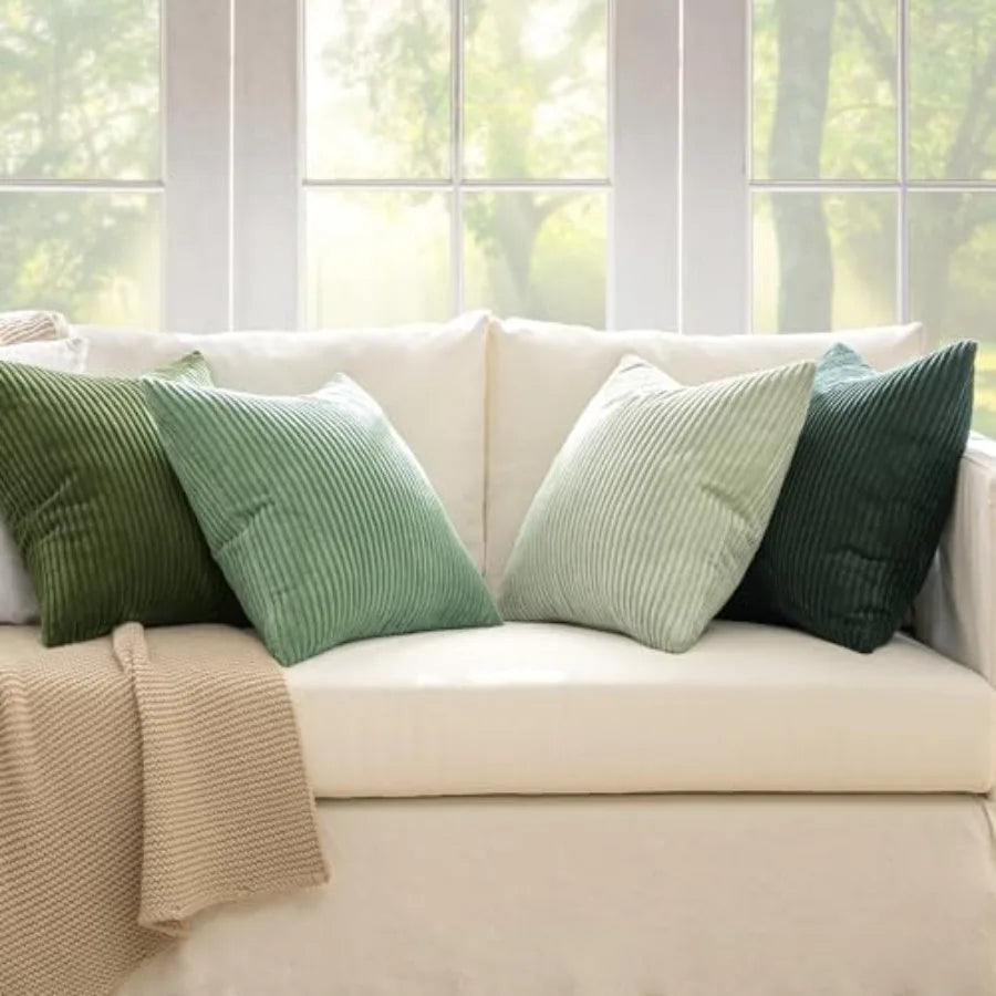 Beige sofa with green and brown cushions in a bright room with large windows.
