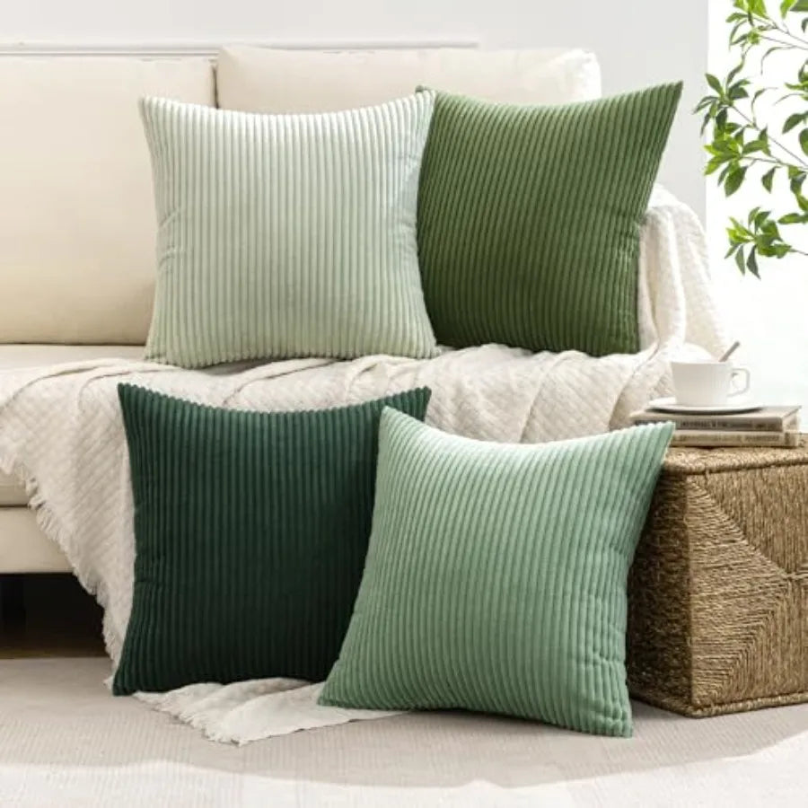 Green and light green ribbed throw pillows on a beige sofa with a plant in the background.