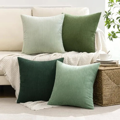 Green and light green ribbed throw pillows on a beige sofa with a plant in the background.