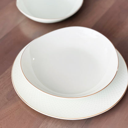 White ceramic bowl with gold rim on a wooden surface