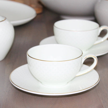 White ceramic tea set with gold trim on a wooden surface