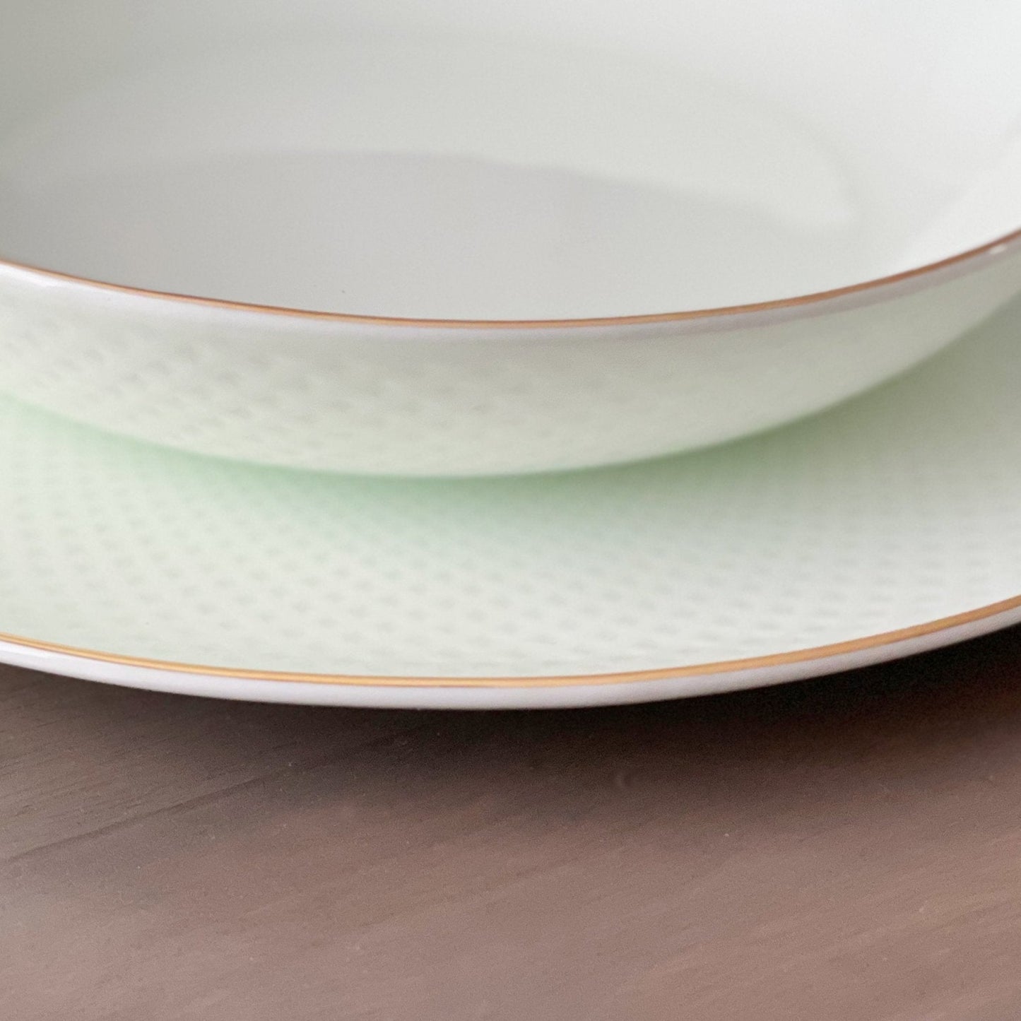 Two stacked ceramic plates with gold rims on a wooden surface