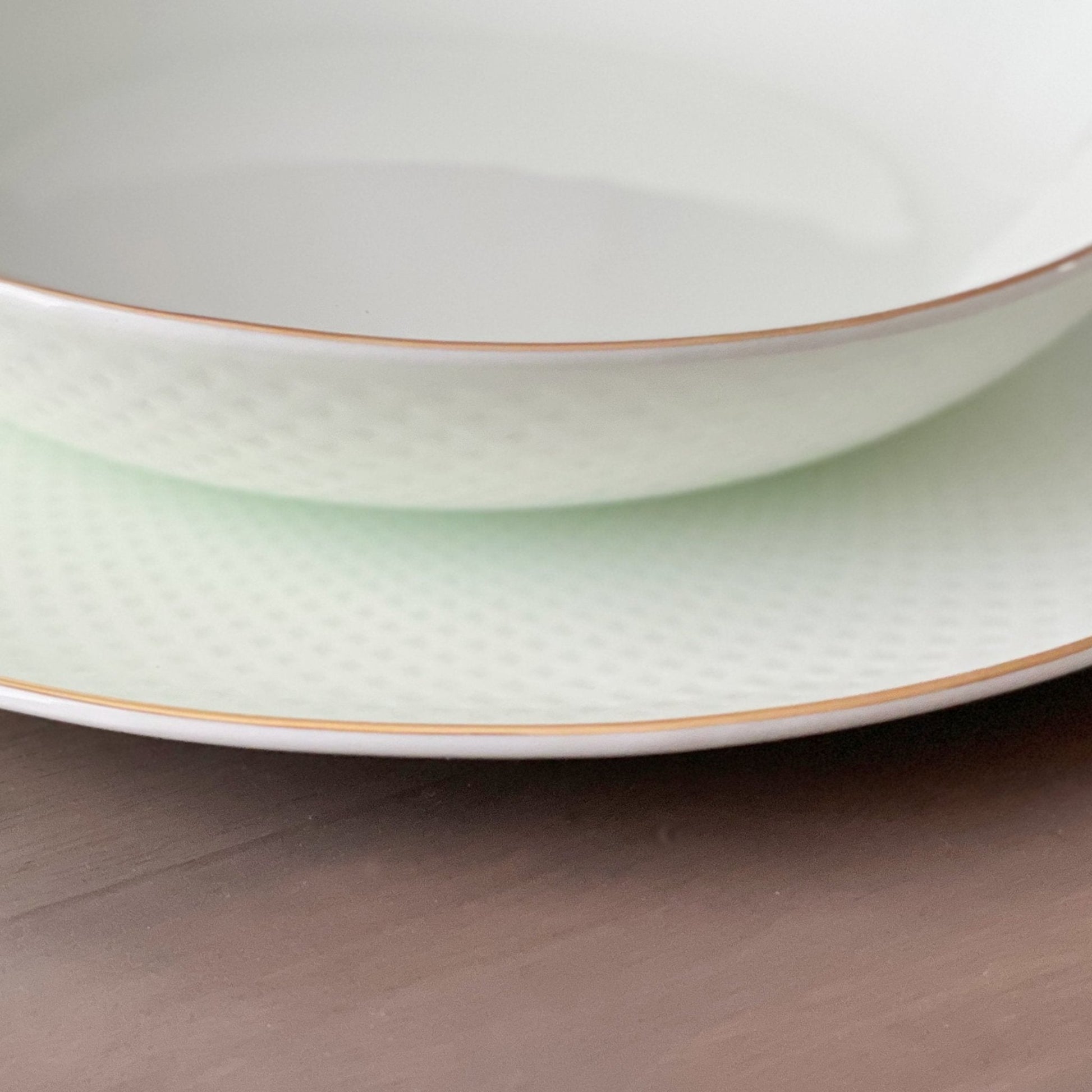 Two stacked ceramic plates with gold rims on a wooden surface