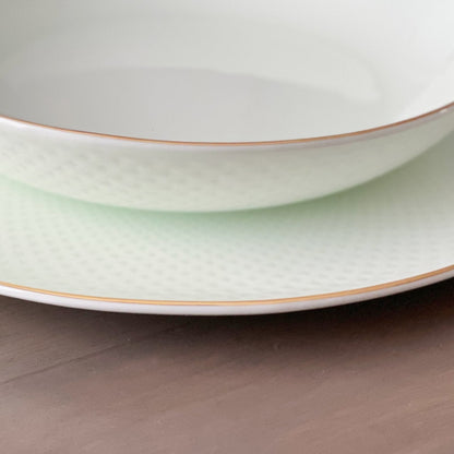 Two stacked ceramic plates with gold rims on a wooden surface