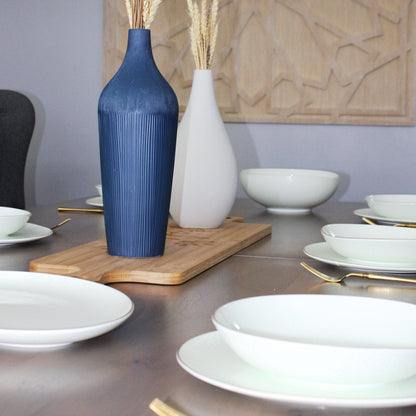 Dining table setting with blue and white vases, plates, and bowls.