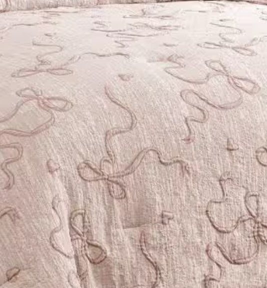 Luxury Blush Pink Bowknot Comforter Set rolled on a soft couch, highlighting versatility as a trendy blush pink comforter set.