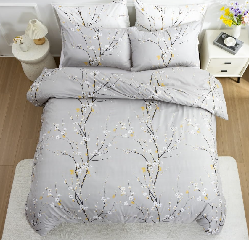 Serene arrangement of sage green floral duvet cover set with textured gray blankets for layered look.