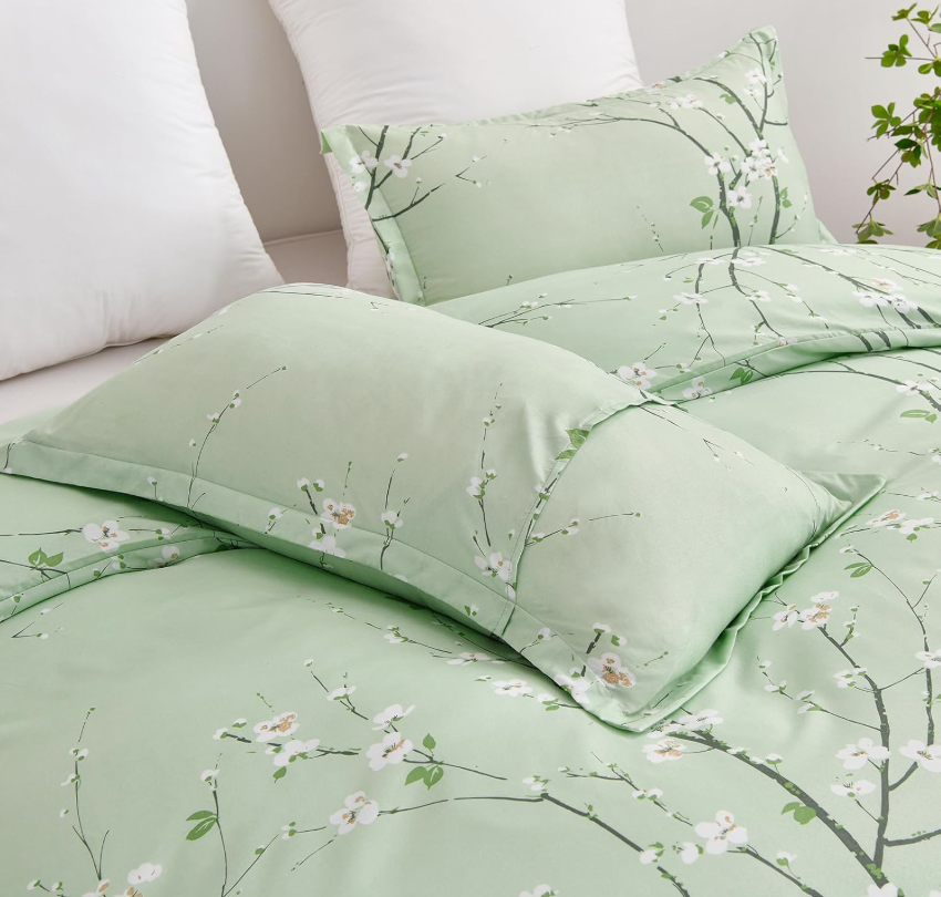 Stylish sage green floral duvet set queen on a neatly made bed with cozy gray throws.