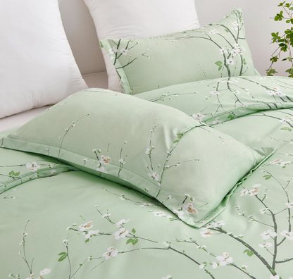 Stylish sage green floral duvet set queen on a neatly made bed with cozy gray throws.