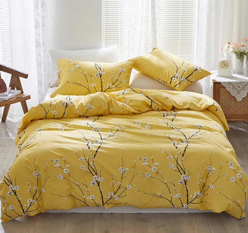 The sage green floral duvet cover set queen styled on a bed with yellow accent pillows.